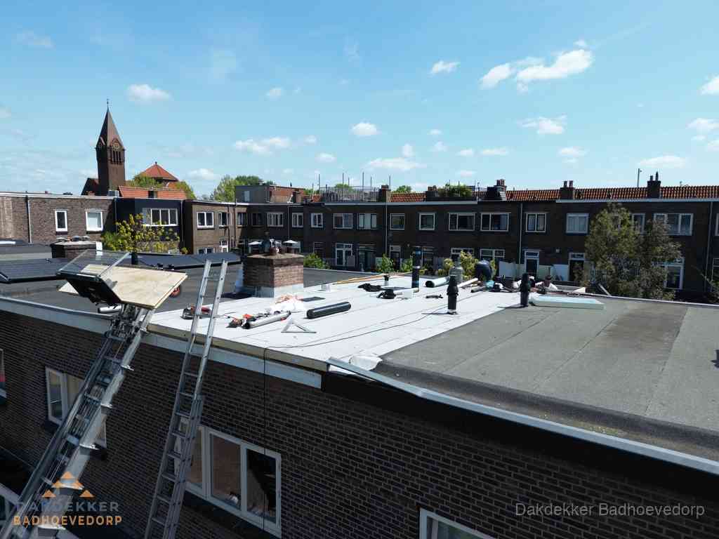 Dakdekkers aan het werk op plat dak in Badhoevedorp